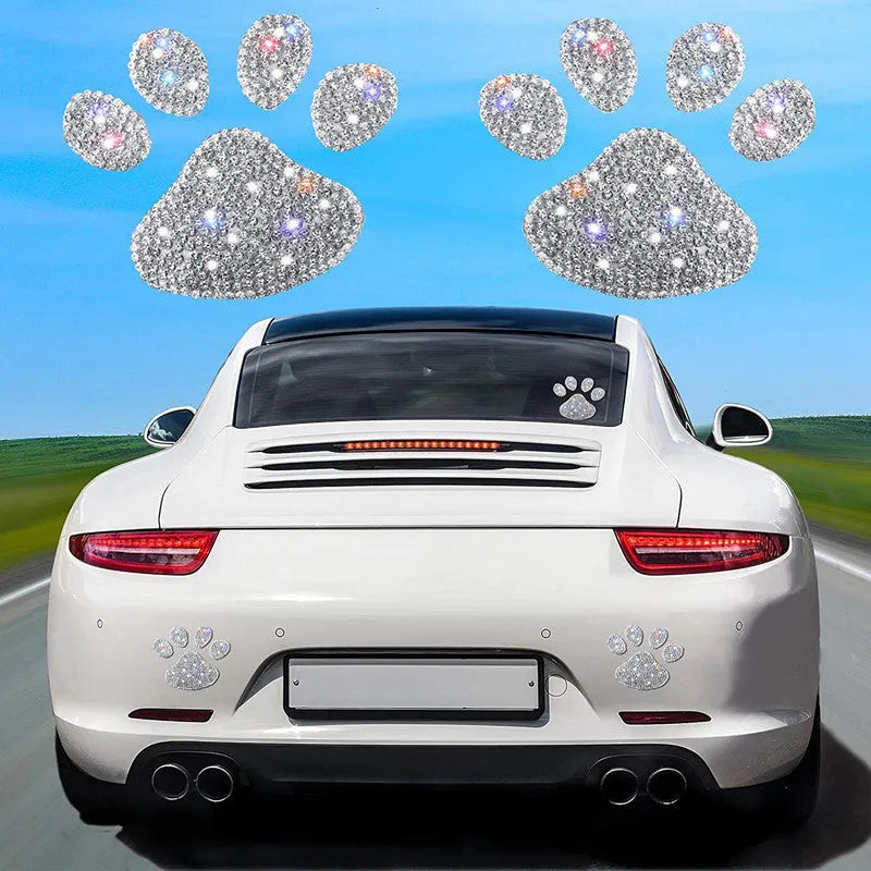 Close-up of a diamond-encrusted glass car sticker in a bear paw or butterfly design on a car surface.
