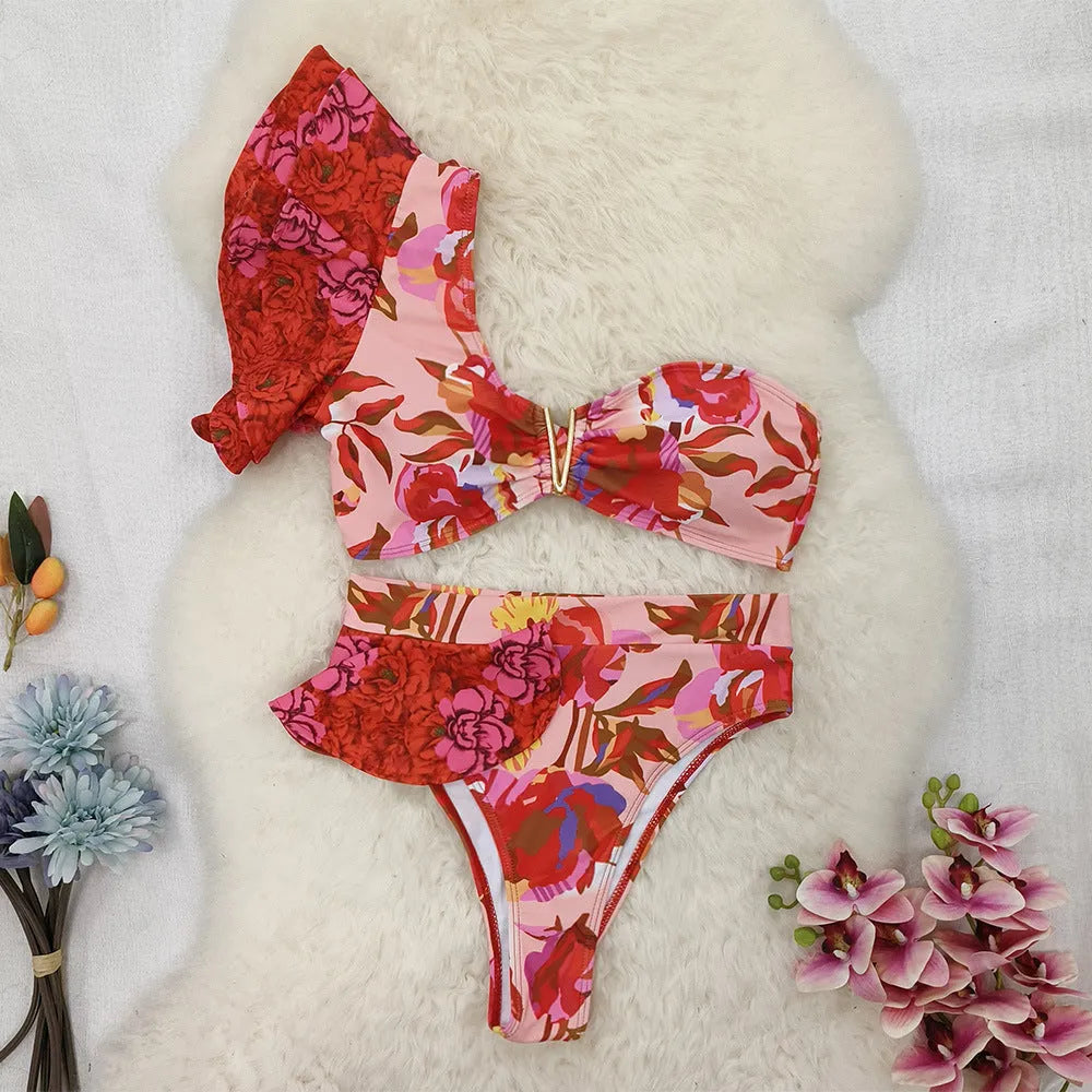 Pink one-shoulder ruffled swimsuit with red floral print and high-waist bikini bottoms