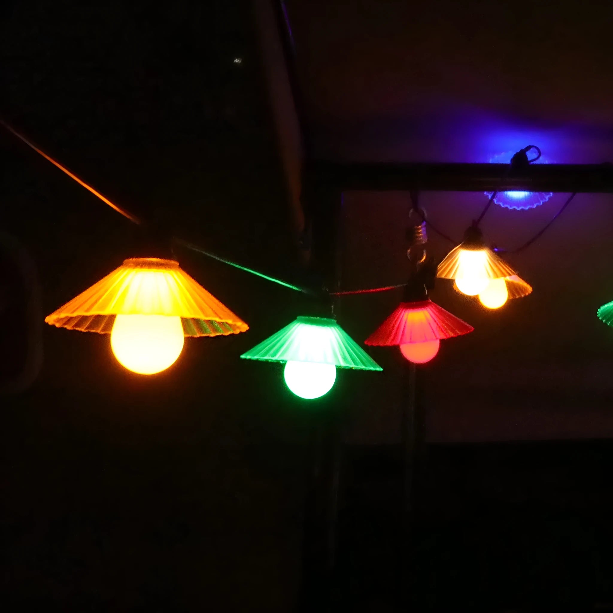 Outdoor LED string lights with white flower-shaped bulbs hanging in a garden.