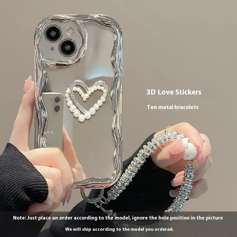 Silver grey silicone phone case for iPhone 15 Pro Max with three-dimensional pearls and chain, electroplated finish, and matching bracelet on a table