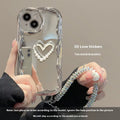 Silver grey silicone phone case for iPhone 15 Pro Max with three-dimensional pearls and chain, electroplated finish, and matching bracelet on a table
