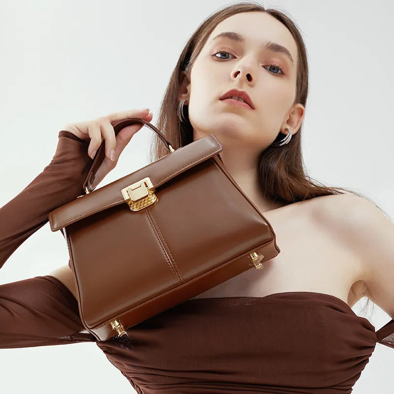 Women's black leather shoulder bag with vachette clasp showing horizontal square shape and adjustable strap