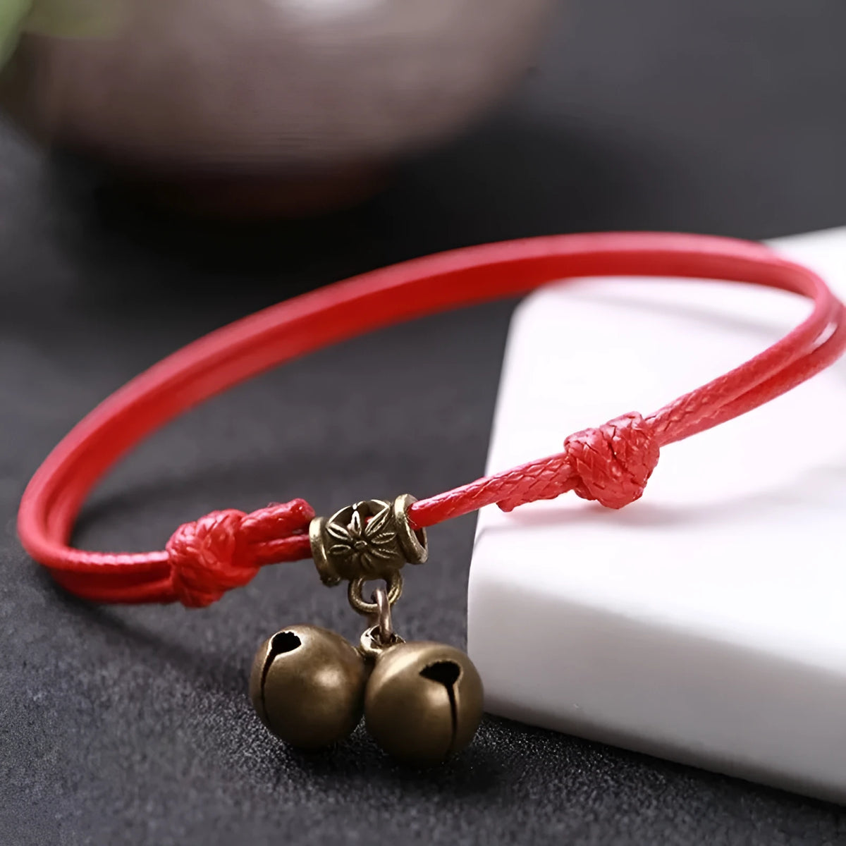 Black nylon rope dog collar with a small brass bell on a wooden background.