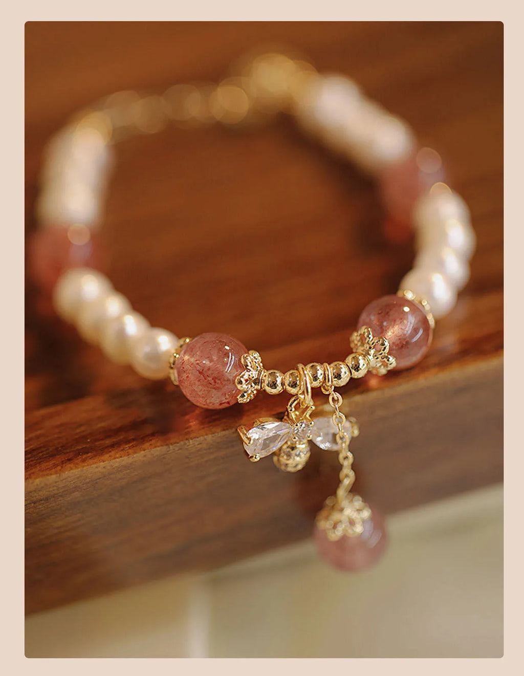 Close-up of a women's hand-strung strawberry quartz crystal bracelet with a decorative bow.