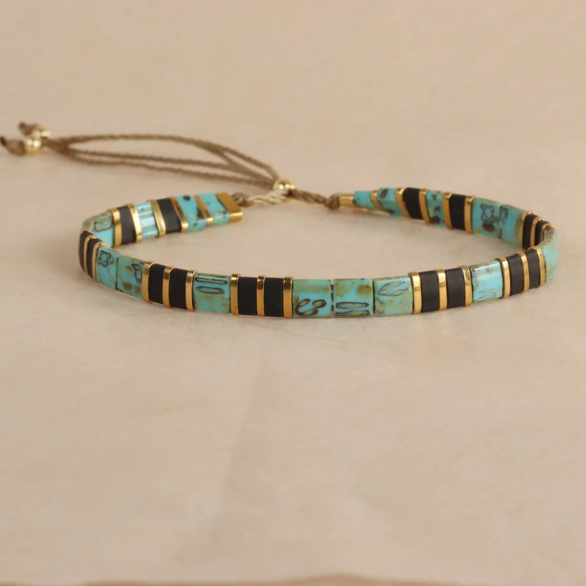 Geometric glass and coloured glaze beaded bracelet with a pull clasp in milky white colour.