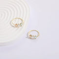 Gold colour geometric triangle ring with horse eye design and tricolour zircon stones on a white background
