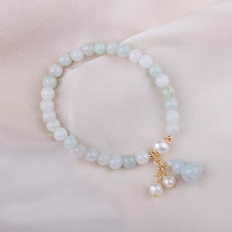Chinese style jade bracelet with gourd charm and pearl accents on wrist