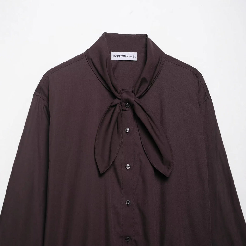 Brown women's loose-fit poplin shirt with long sleeves and a built-in bow tie detail.