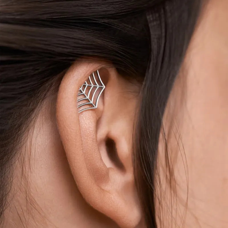Close-up of geometric spider web patterned metal stud earrings in a gold electroplated finish.