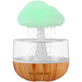 White cloud-shaped portable humidifier with coloured night light on a wooden table.