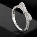 Silver bow-shaped ring with sparkling zircon crystal stones on a finger.