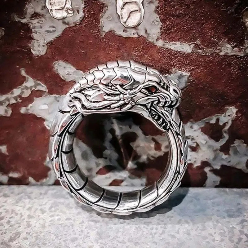 Vintage dragon male ring in ancient silver metal on a plain background.