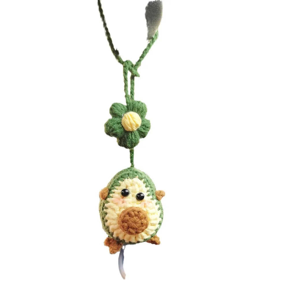 Handmade crocheted avocado-shaped car pendant in wool, shown in three colour variations.
