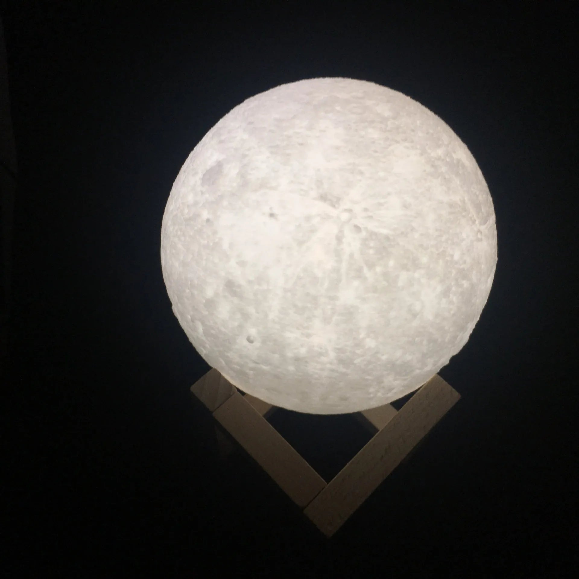 3D printed white moon lamp with detailed craters on a wooden stand, showing touch ring at base