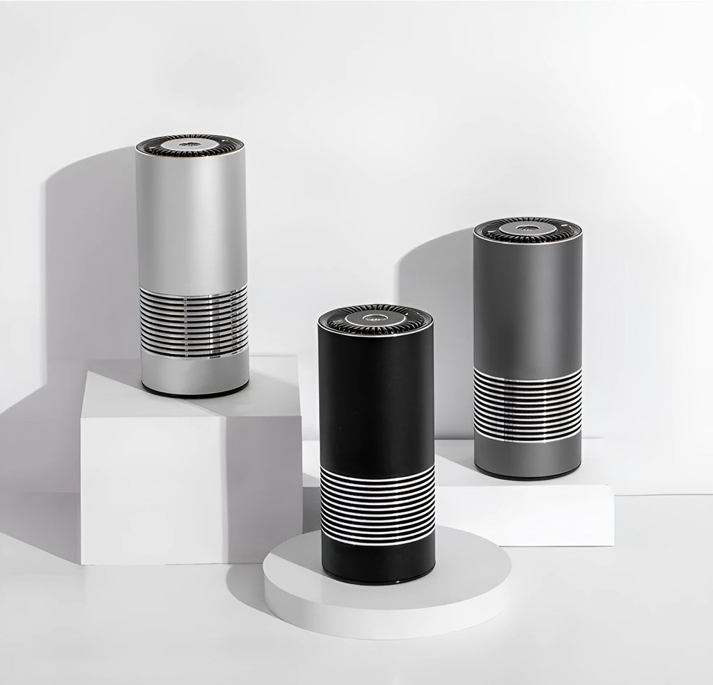 Compact aluminium alloy car air purifier in black, silver, or metallic grey for dashboard use.