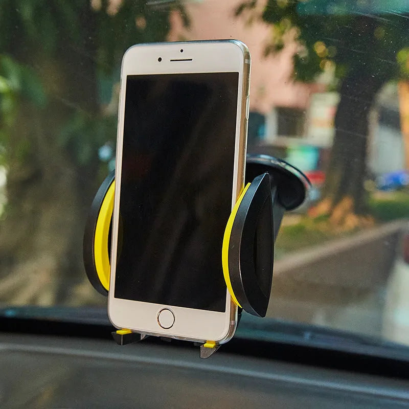 Red U-shaped car phone holder with suction cup base and adjustable clamp arms on a vehicle dashboard