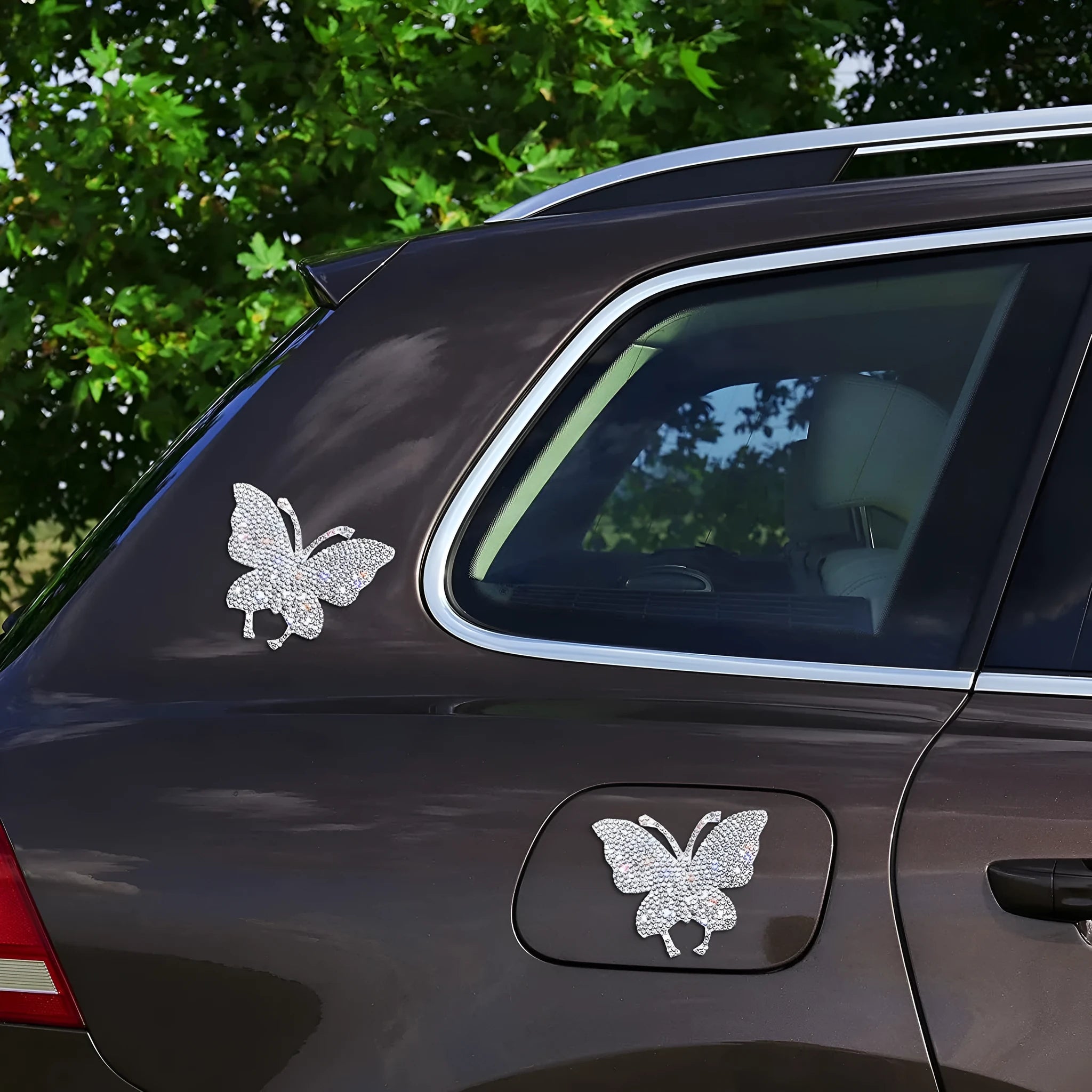 Close-up of a diamond-encrusted glass car sticker in a bear paw or butterfly design on a car surface.