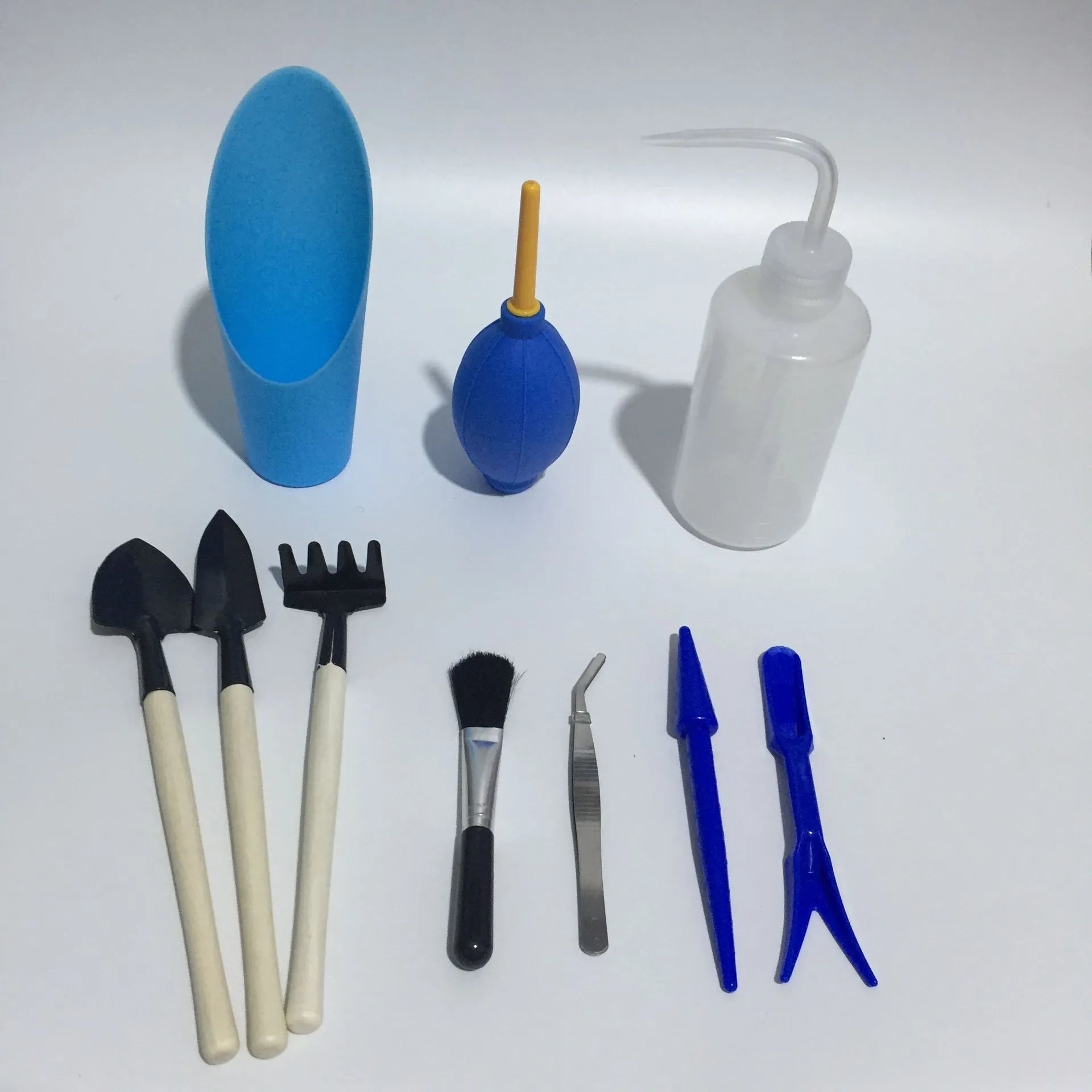 Succulent gardening tool set with plastic watering can, mini shovel, rake, tweezers, and a small bucket on a table