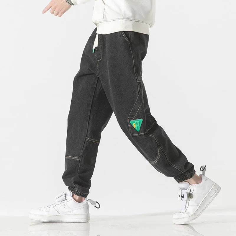 Men's loose-fit tapered cotton trousers in grey showing mid-waist design and tapered leg silhouette
