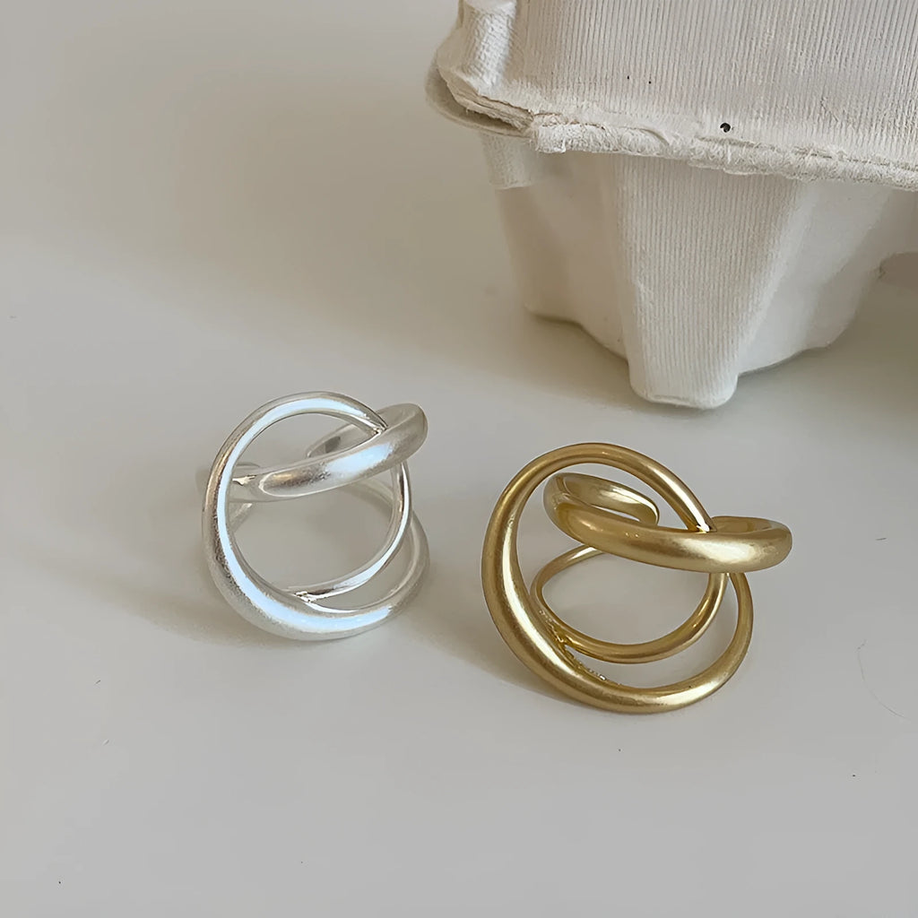 Geometric open ring for women with 3D interlaced matte metal design in gold and silver colour options.