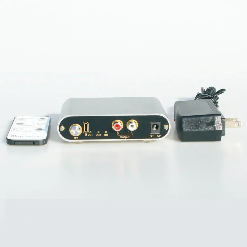 Silver aluminium audio source switch unit with front-panel buttons and infrared remote control.