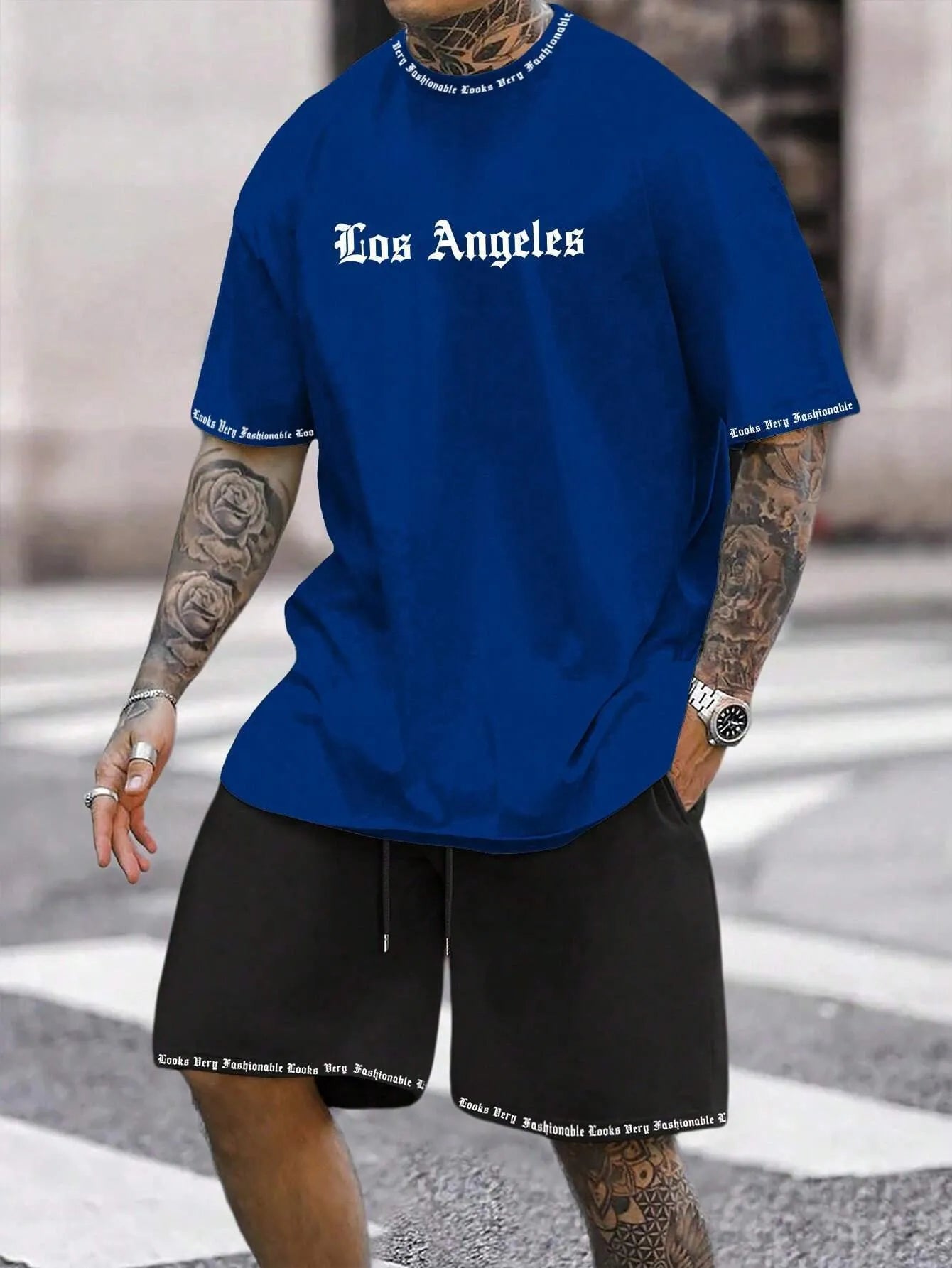 Man wearing a blue printed short-sleeve top and matching shorts from a two-piece sports casual set.
