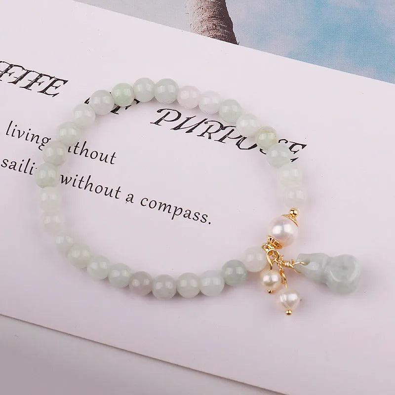 Chinese style jade bracelet with gourd charm and pearl accents on wrist