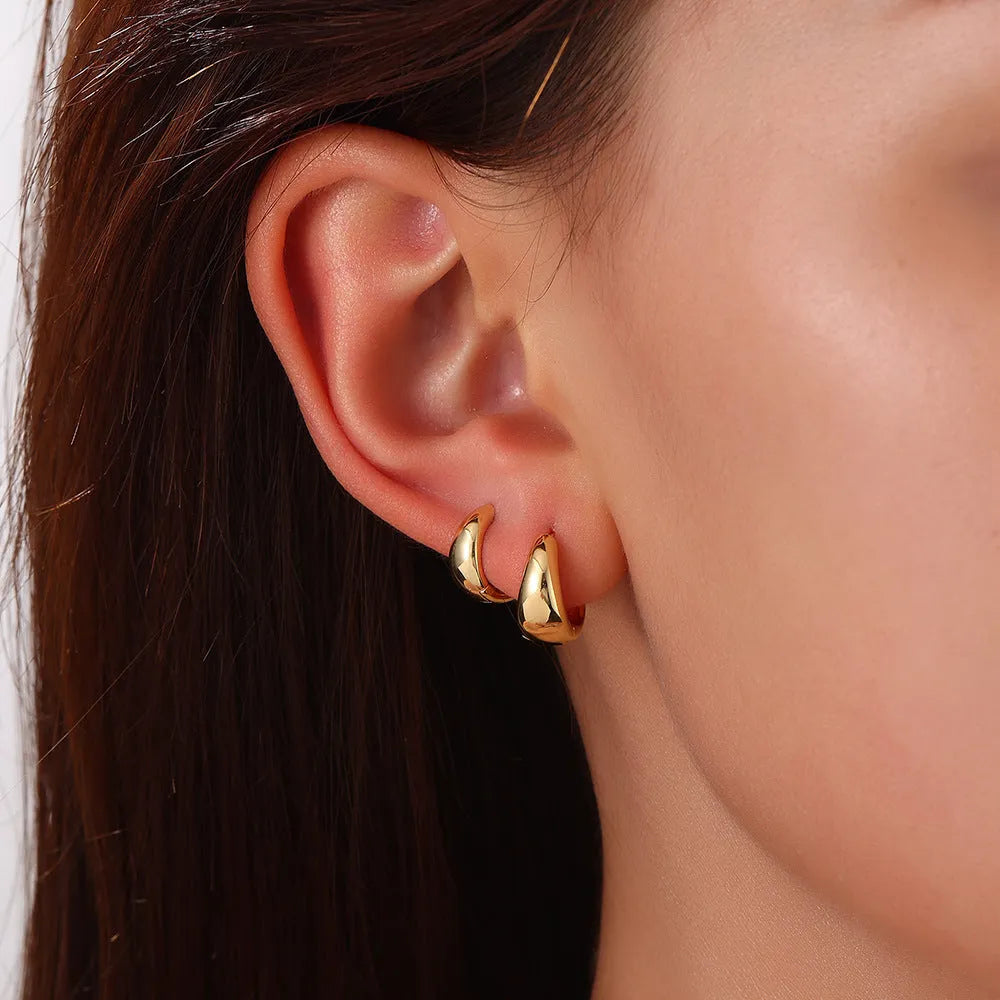 Drop-shaped copper earrings set of three sizes in gold finish on a white background