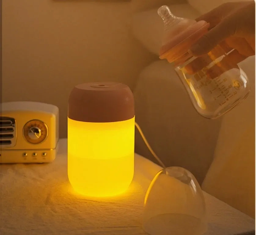 White cylindrical mini USB aromatherapy humidifier on a desk with charging cable.