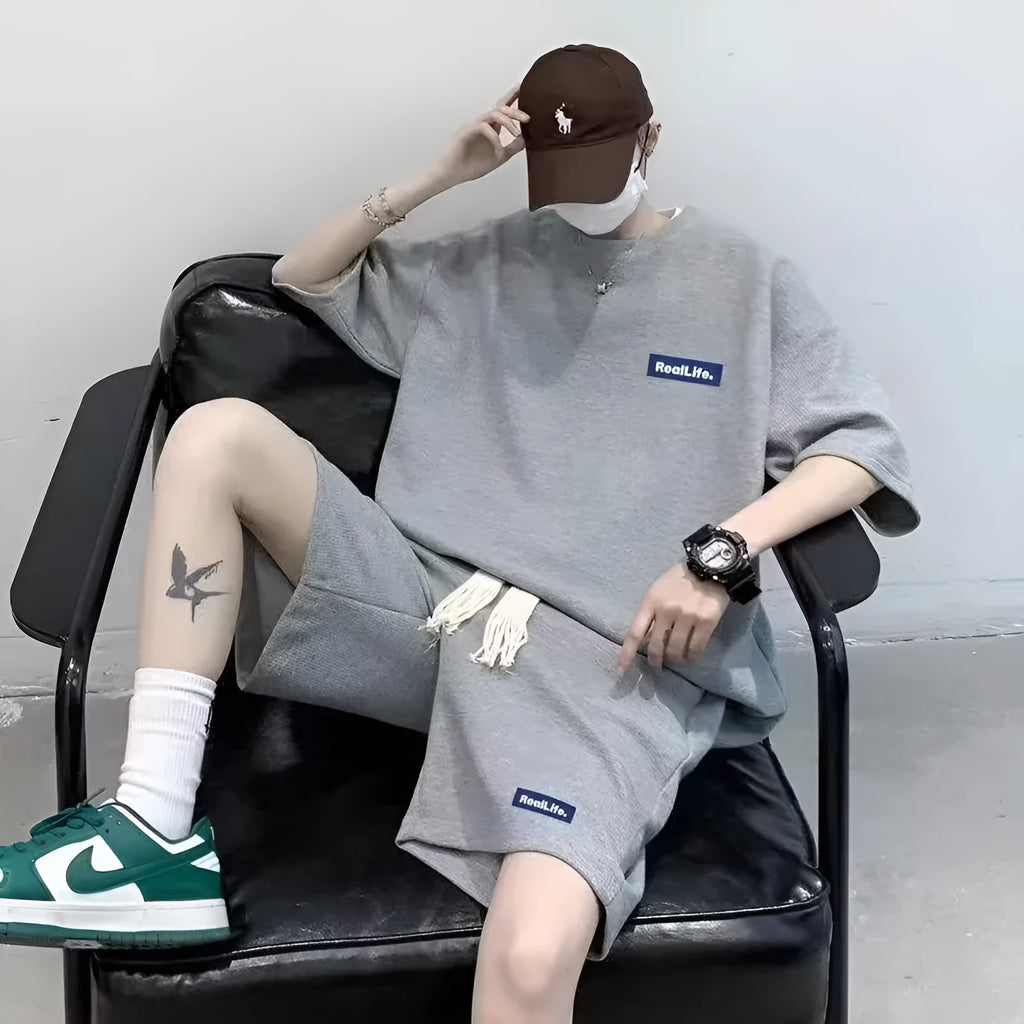 Man wearing a grey waffle-textured short sleeve leisure top and matching shorts.