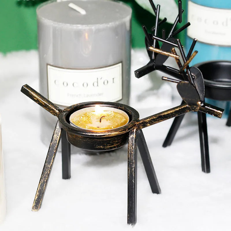 Black iron Christmas candlestick holder with decorative elk design on a festive table.