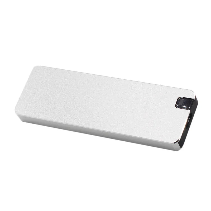 White portable external SSD with metal shell and USB cable next to a laptop.