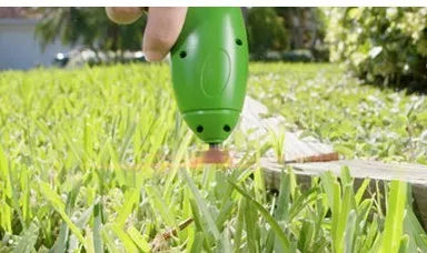 Cordless zip tie lawn trimmer with extension pole and protective debris shield on grass.