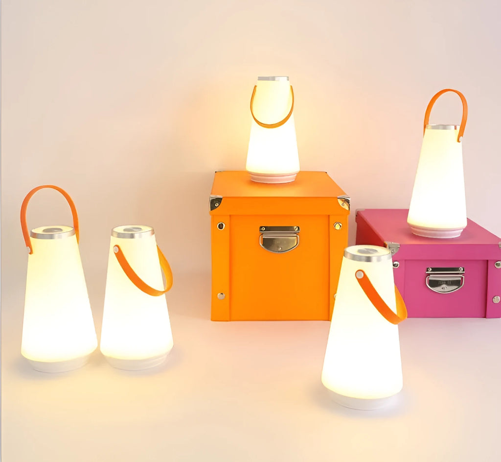 White rechargeable LED bedside lantern with USB cable on a table.
