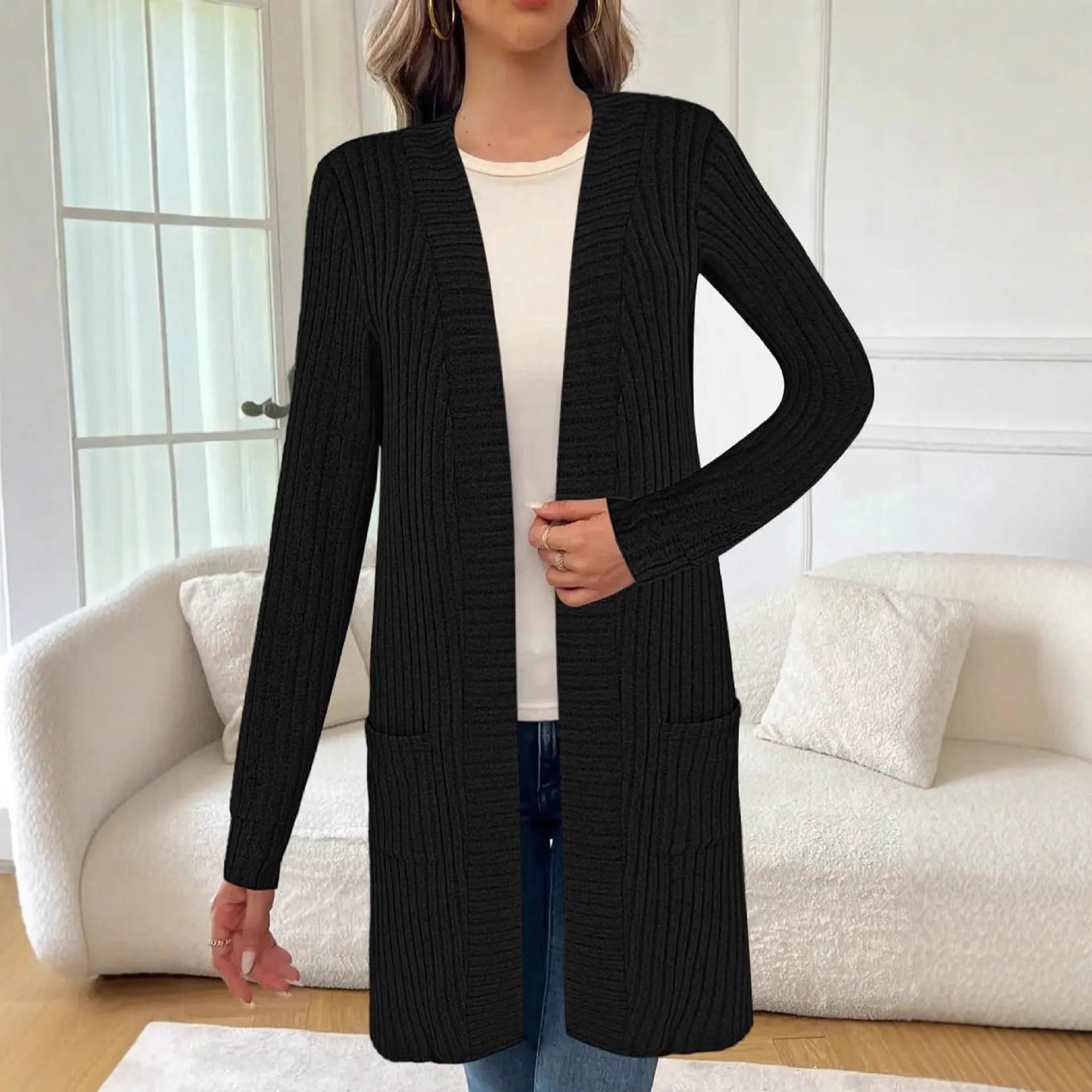 Woman wearing a loose grey long sleeve knitted cardigan jacket with pockets.