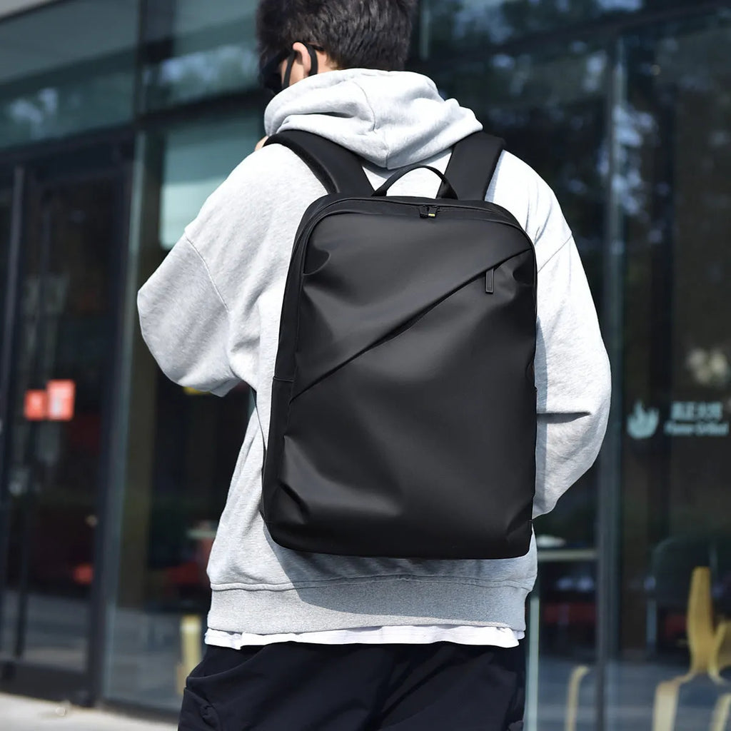 Men's large capacity waterproof backpack in black colour showing PU leather construction and computer bag accommodation