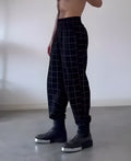 Men's plaid trousers with apron waistband, relaxed fit, and side pockets.
