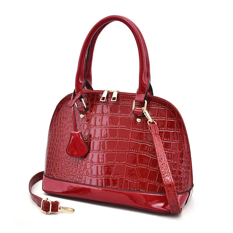 Shiny black PU leather crossbody bag with a structured shell shape, shown with a shoulder strap.