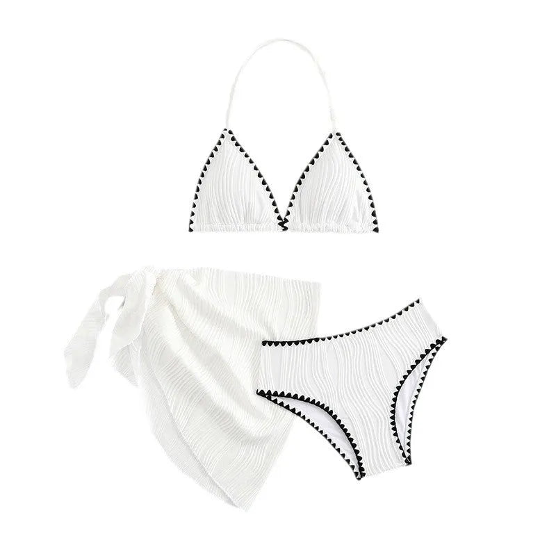 Solid white three-piece girls swimsuit set with top, pants, and skirt on a beach setting.