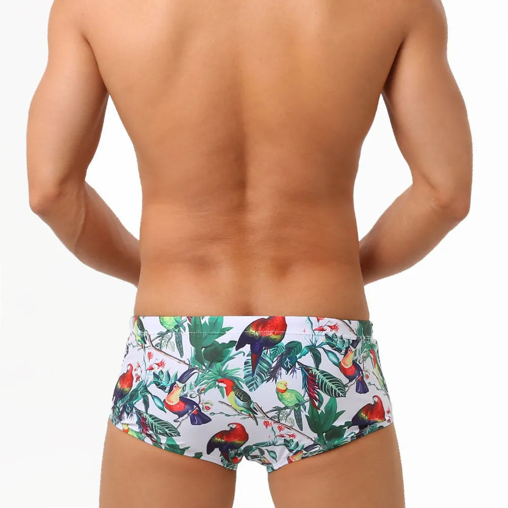Men's navy blue swimming trunks with colourful flower and bird print pattern.