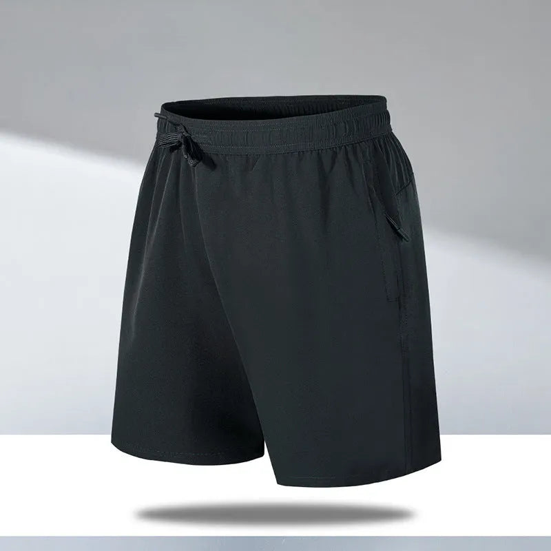 Man wearing loose-fit black quick-dry polyester sports shorts on a beach