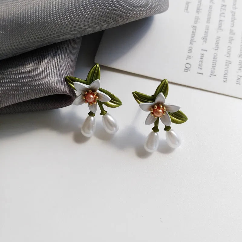 Women's alloy flower earrings with needle camellia design in sterling silver colour, shown as clip-on and ear stud styles