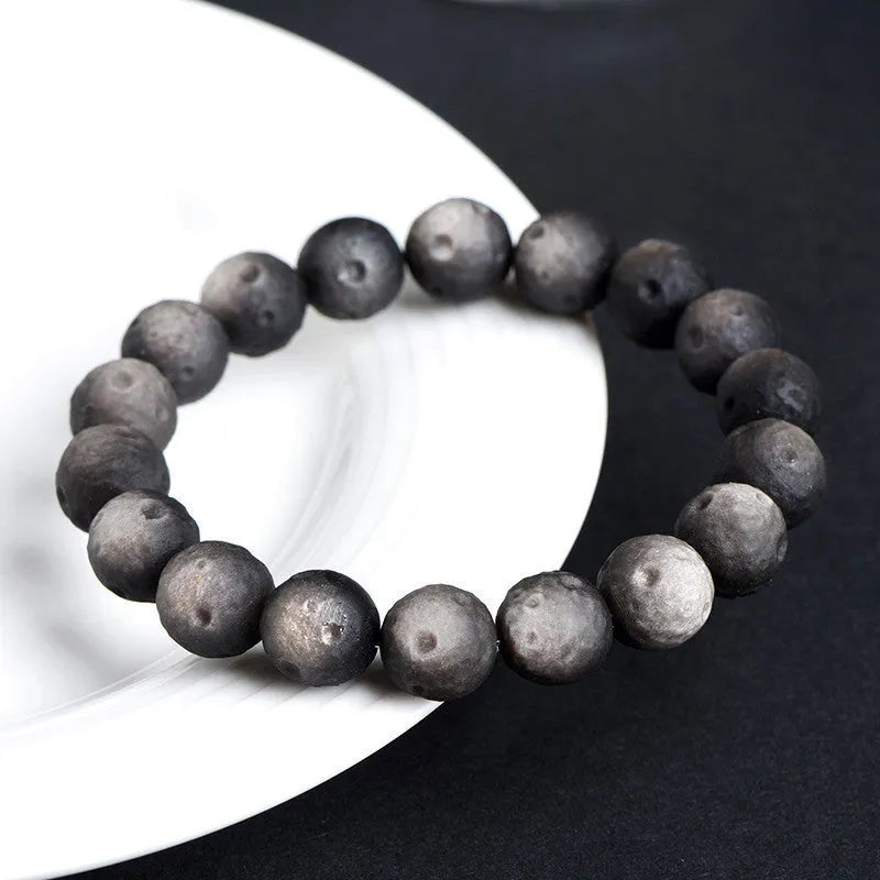 Natural obsidian crater ball bracelet in silver stone or gold finish, showing textured bead detail.