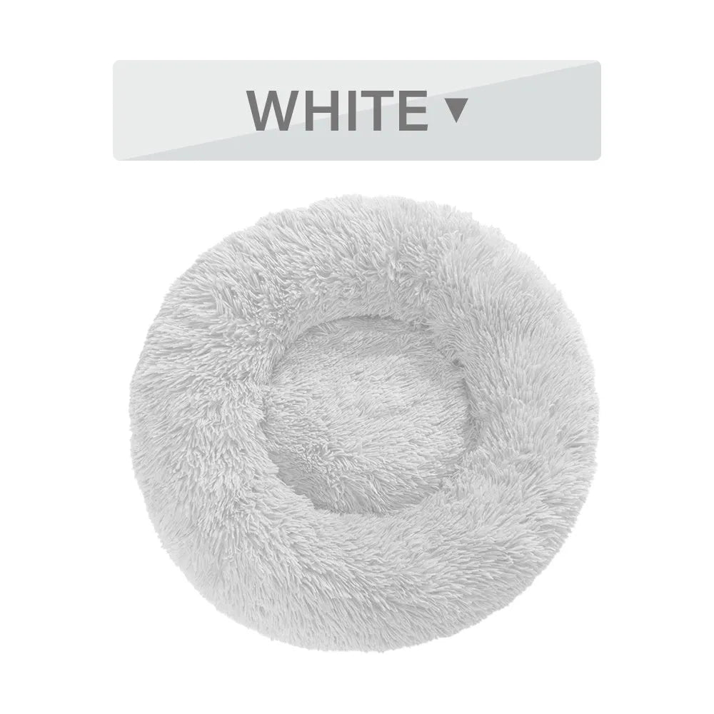Fluffy grey donut-shaped dog bed with raised plush edge on a wooden floor.