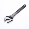 10-inch black high carbon steel adjustable open-end wrench on a workbench.