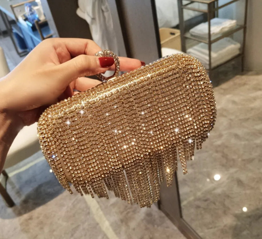 Silver ladies fringed hand bag with shiny diamond embellishments and clasp closure on a plain background