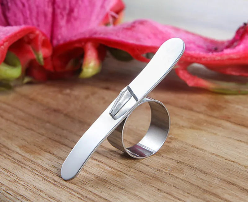 Stainless steel ring orange peeler on a countertop with citrus fruits nearby, showing compact silver tool