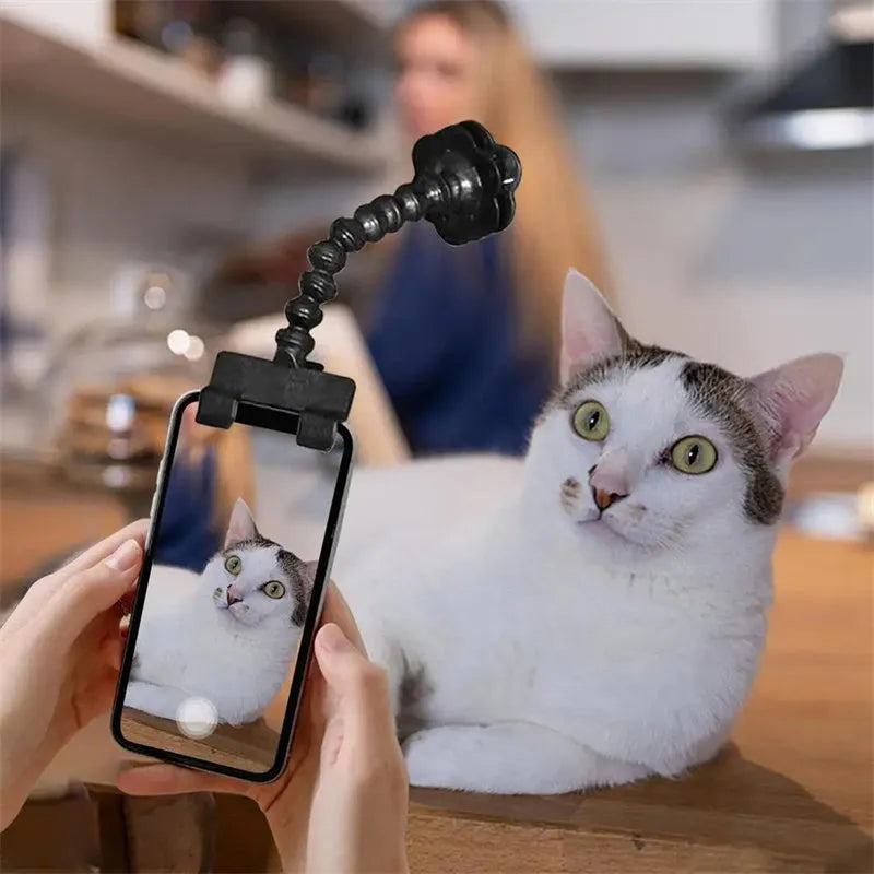 Black plastic pet photography clip holding a phone, with a rotating arm to grip dog or cat treats for photos.