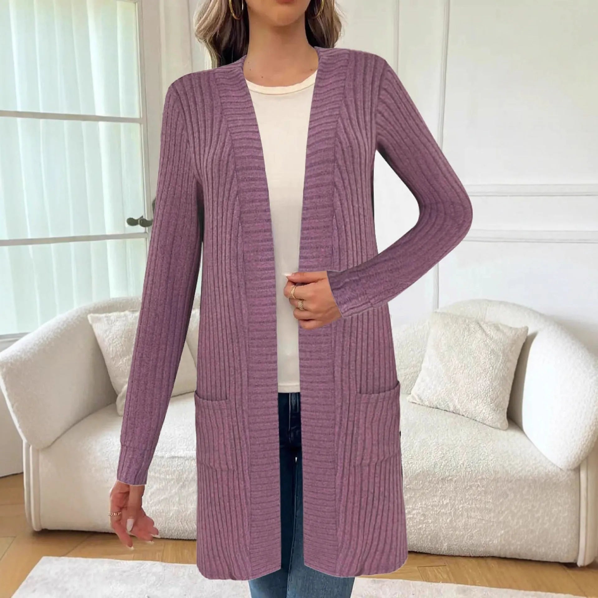 Woman wearing a loose grey long sleeve knitted cardigan jacket with pockets.