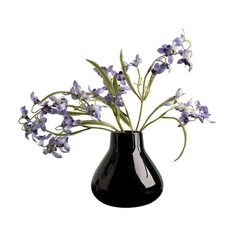 Black ceramic vase with round belly shape and two white flower ornaments arranged decoratively